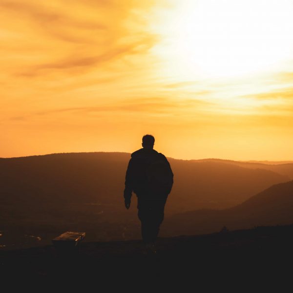Silhouette of man walking in the mountains towards sunset