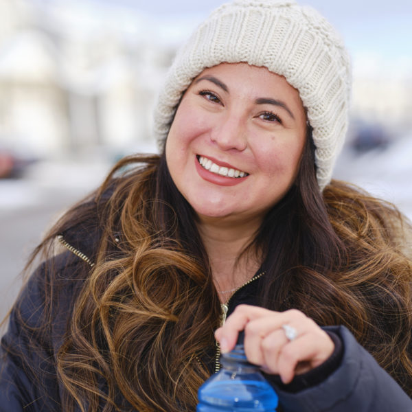 Woman smiling and opening a drink outdoors in winter